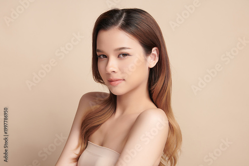 A beautiful young Asian woman with clean, fresh skin against a beige background. Skincare, facial treatment, cosmetology, beauty, and spa. An elegant portrait of an Asian woman.
