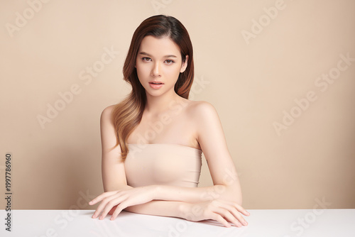 A beautiful young Asian woman with clean, fresh skin against a beige background. Skincare, facial treatment, cosmetology, beauty, and spa. An elegant portrait of an Asian woman.