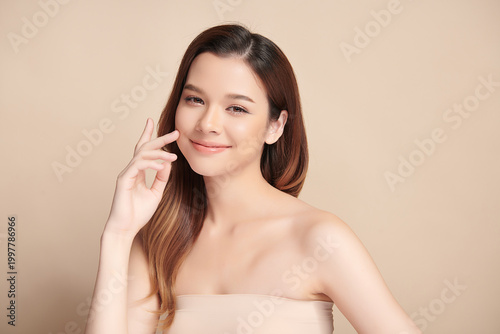 A beautiful young Asian woman with clean, fresh skin against a beige background. Skincare, facial treatment, cosmetology, beauty, and spa. An elegant portrait of an Asian woman.