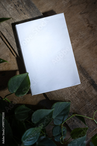 Clean Blank Paper Mockup with Green Leaves on Wooden Background, Flat Lay Copy Space