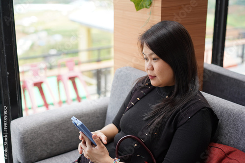 Close up of Asian woman concentrating while using smartphone in cafe environment