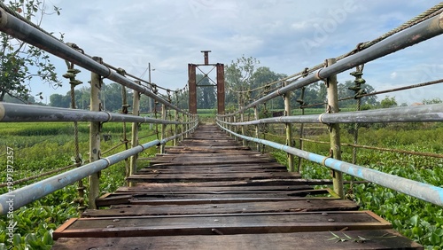 Rustic Suspension Bridge Over Water with Wooden Structure and Scenic Natural Landscape View