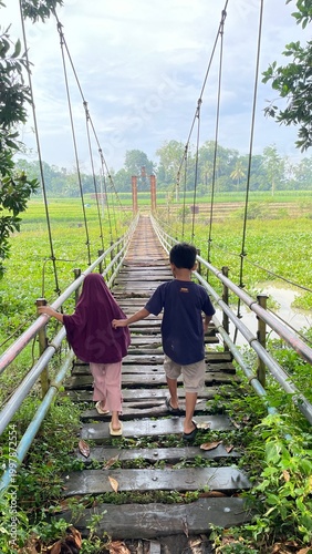 Children Walking on Suspension Bridge Outdoors in Lush Green Nature Landscape with Scenic View