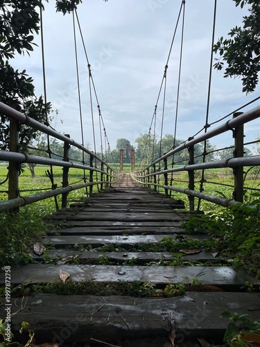 Rustic Suspension Bridge Over Water with Wooden Structure and Scenic Natural Landscape View