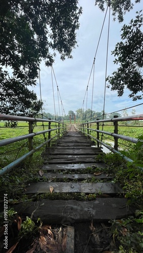 Rustic Suspension Bridge Over Water with Wooden Structure and Scenic Natural Landscape View