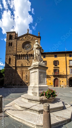 Sunny day image of an old European square. A statue stands in the center, a large church is visible. Blue sky with white clouds