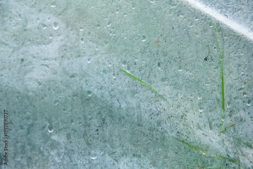 A captivating macro photograph featuring natural morning dew droplets and condensation collected on the surface of a sheet of clear plastic. The image captures the foggy effect created by countless sm