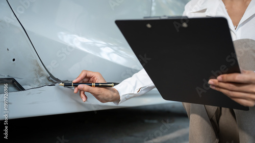 Foto Close-up of insurance adjuster inspecting car body damage, holding clipboard and pen, documenting dented vehicle panel for auto repair claim assessment