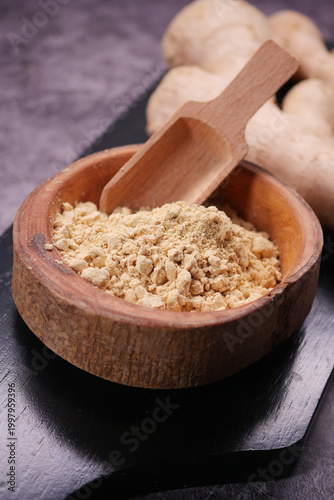 Bild auf Leinwand Ginger powder in wooden bowl with scoop on dark surface