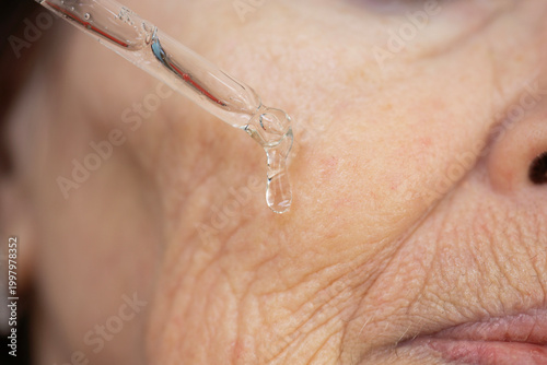 Foto advanced anti-aging face serum portrait applying liquid dropper with exosomes,