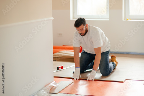 Tableau sur toile Worker installing new laminate flooring planks in building