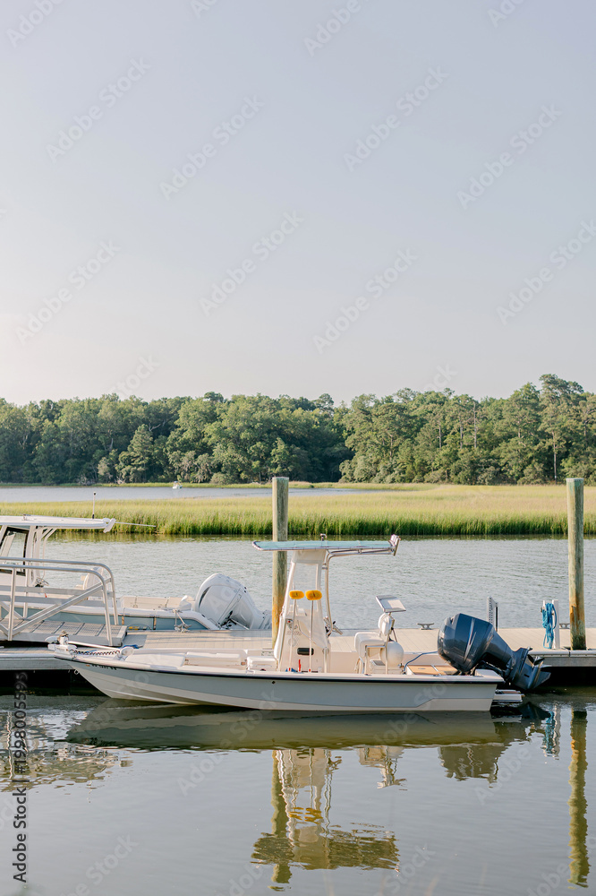 Fototapeta premium Small motorboats moored at a wooden pier in a marsh at sunset
