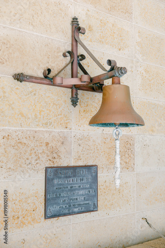 Fotografía Antique ship bell and commemorative bronze plaque on a stone wall