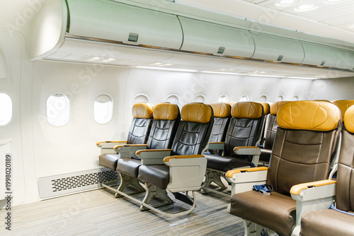 Foto Empty airplane cabin with rows of leather economy seats, overhead bins, and windows, showcasing a clean, modern interior ready for passengers