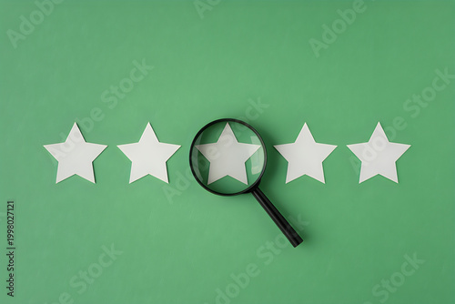 Magnifying glass over a white paper star on a bright green background