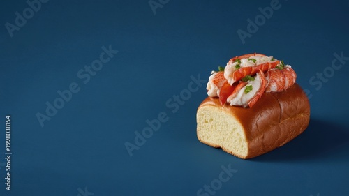 Lobster roll with chunks of cooked lobster meat on a soft brioche bun against a blue background