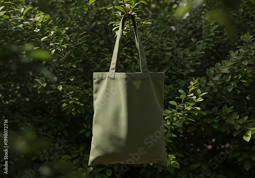 Olive green tote bag hanging against green foliage with copy space