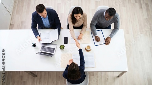 Overhead: Professional job interview handshake at a modern office table, a diverse business team welcomes a new candidate. Hiring and career success concept.