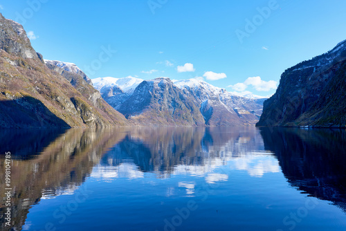 Stunning Mirror Reflection of Snow-Capped Mountains in a Calm Norwegian Fjord under Blue Sky