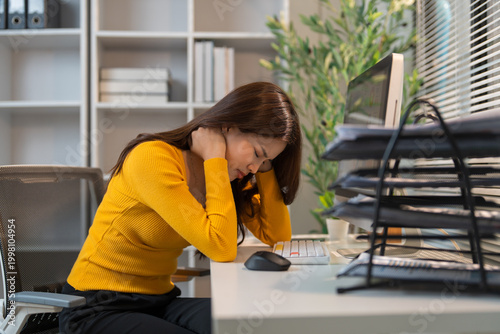 Young woman experiencing neck pain at office desk