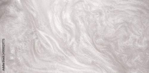 Shimmering silver abstract background. Liquid glitter paint texture waves and swirls. Beautiful shiny white glitter texture. Metallic silver paint close-up as a holiday background.