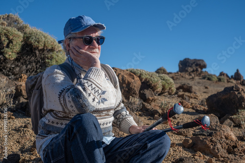 Photos Senior Man Hiking Resting in Rocky Landscape With Trekking Poles and Backpack