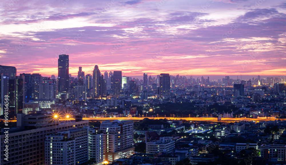 Obraz premium BANGKOK, THAILAND - MAY 15, 2015: A breathtaking sunrise view over the Bangkok skyline, featuring a vibrant purple and orange sky during twilight.