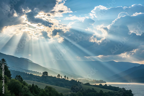 Sunlight breaks through clouds over serene mountain lake landscape