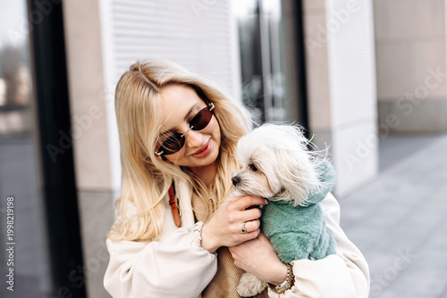 Woman cuddling small Maltese dog, close emotional lifestyle portrait