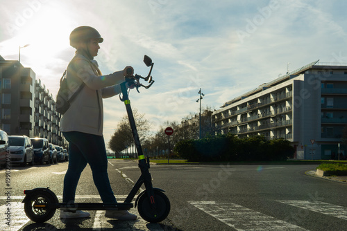 Woman with helmet using electric scooter in city