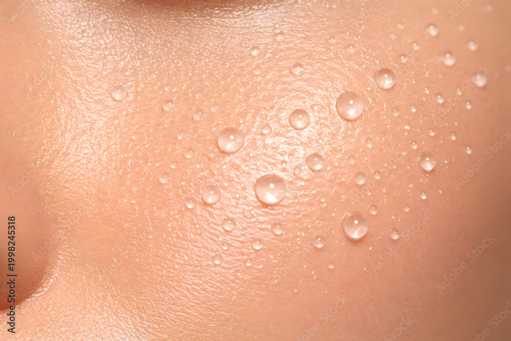 Fototapeta premium Extreme macro of radiant human skin with fresh water droplets. Concept of hydration, skincare, moisture, and natural beauty texture with visible pores.