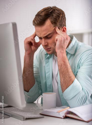 Man with headache at computer.