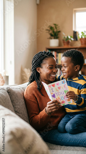 Black child giving handmade card to black mother, emotional connection, soft focus