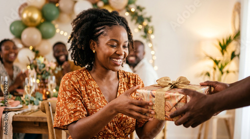 Black mother receiving a gift box, detail of the family celebration, party with decorations and balloons.