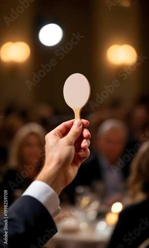 Hand holding auction paddle during annual charity auction event  