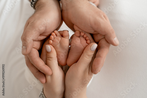 Close-up of a newborn baby's legs in its parents' arms