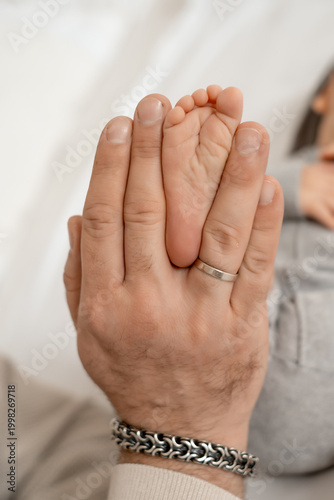 Close-up of a newborn baby's legs in its parents' arms