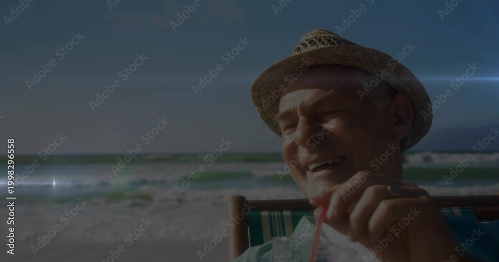 Fototapeta premium Sitting man sipping from plastic cup with red straw at shoreline, wearing straw hat, copy space