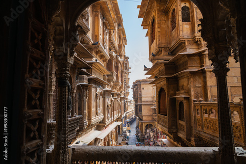 View of a narrow street lined with carved sandstone buildings framed through an arch inside Jaisalmer Fort, Rajasthan.