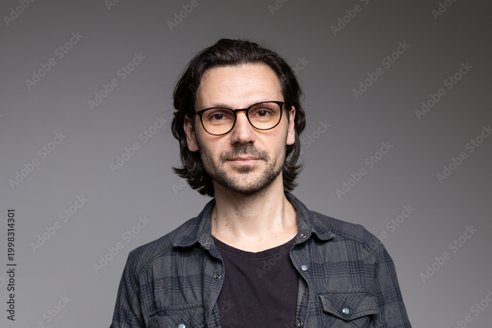 Obraz premium Smart professional man in glasses and plaid shirt with slight smile