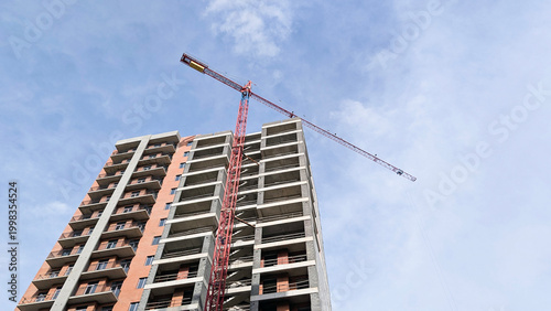 Foto Tower crane standing tall next to a multi story residential building frame, show