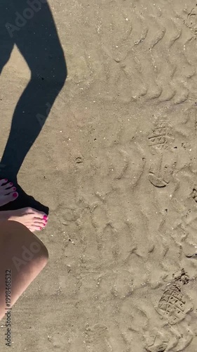 Piedi con smalto rosa sulla sabbia