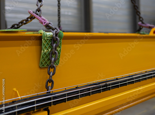 Canvastavla Heavy duty chain attached to yellow overhead crane beam in manufacturing plant