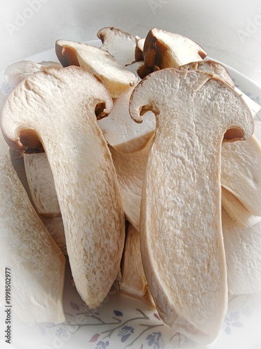 Close-up of fresh king oyster mushrooms stacked together, natural organic edible mushrooms with brown caps and white stems, healthy food ingredient concept
