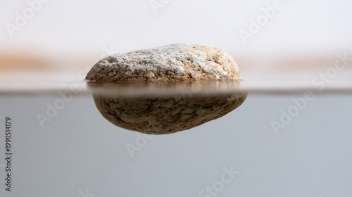 Textured Stone Partially Submerged in Still Water Reflecting its Form, Creating a Serene and Balanced Abstract Natural Scene with Soft Lighting