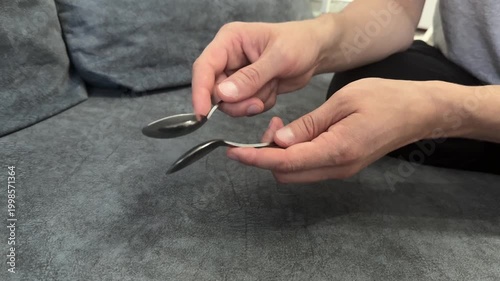 Hand tapping a spoon against a spoon