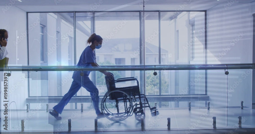 Obraz premium Walking nurse wearing blue scrubs and mask pushing wheelchair along clinic hall with glass railing