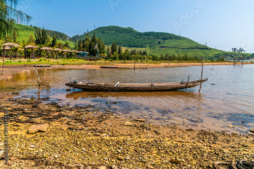 Konstfotografi A view from the shore past a sampan boat on the Lap An Lagoon in Vietnam on a br