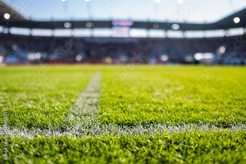 Close-up low-angle view of a white chalk boundary line on a vibrant green soccer pitch with a blurred stadium in the background.