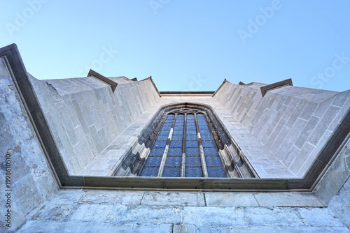 Gothic Window of St Martins Cathedral in Bratislava Slovakia with Low Angle Worms Eye Perspective View of Stone Walls and Clear Blue Sky on Historic European Religious Landmark Building.